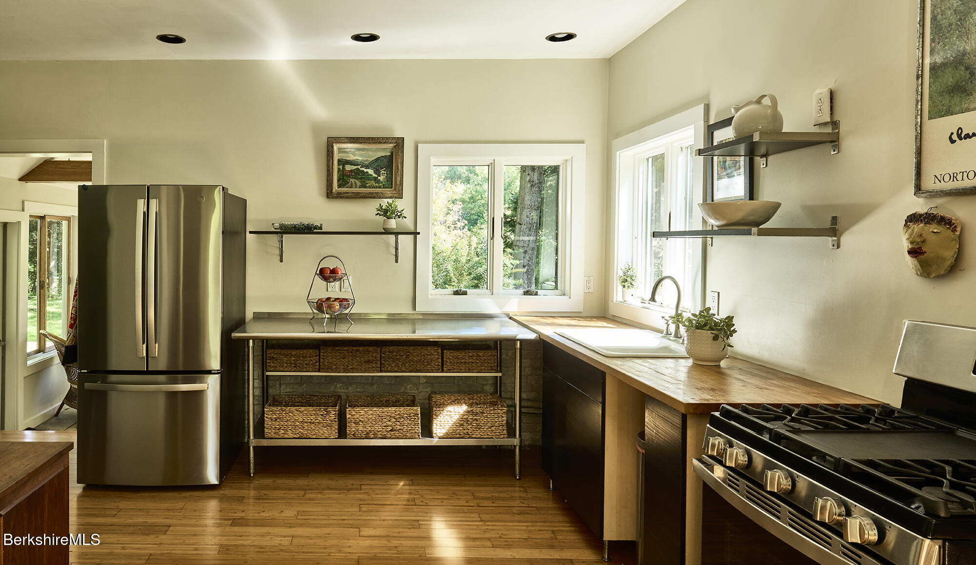 Kitchen with a basket-lined island, wood countertops, stainless appliances, and windows overlooking greenery.