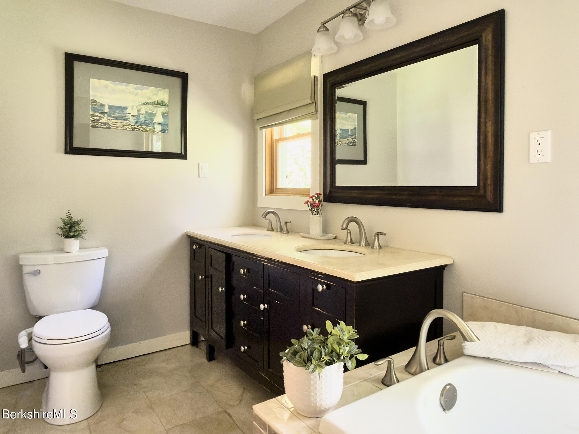 Bathroom with a dark double vanity and soaking tub.