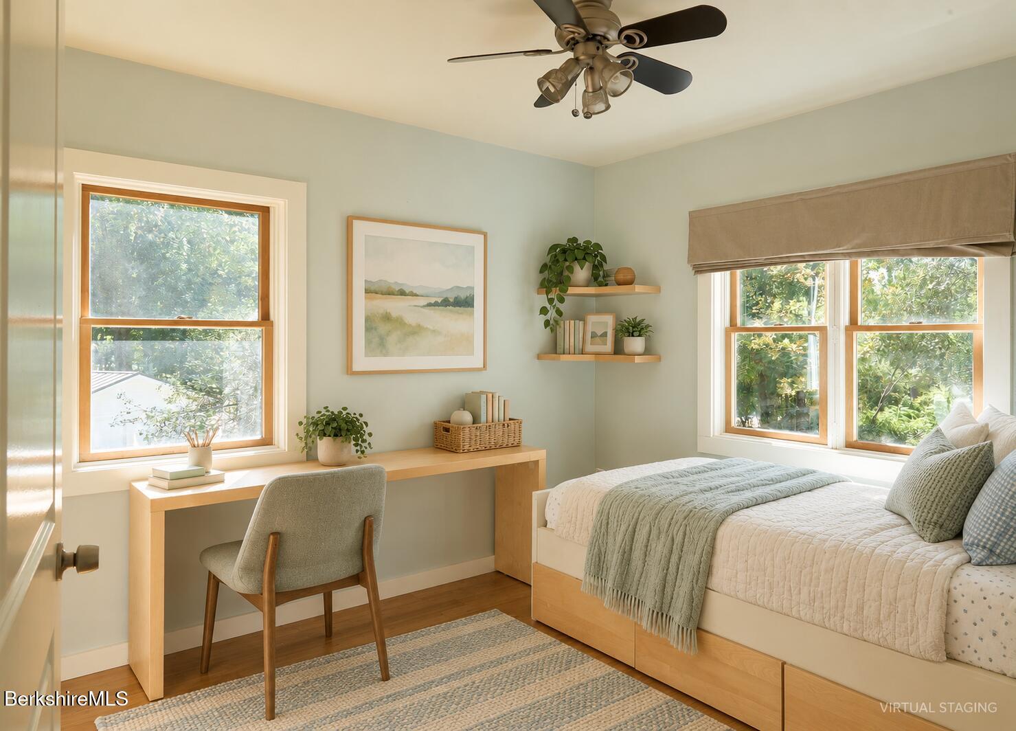Virtually staged bedroom with a bed beside a wooden desk, two bright windows, and a ceiling fan.