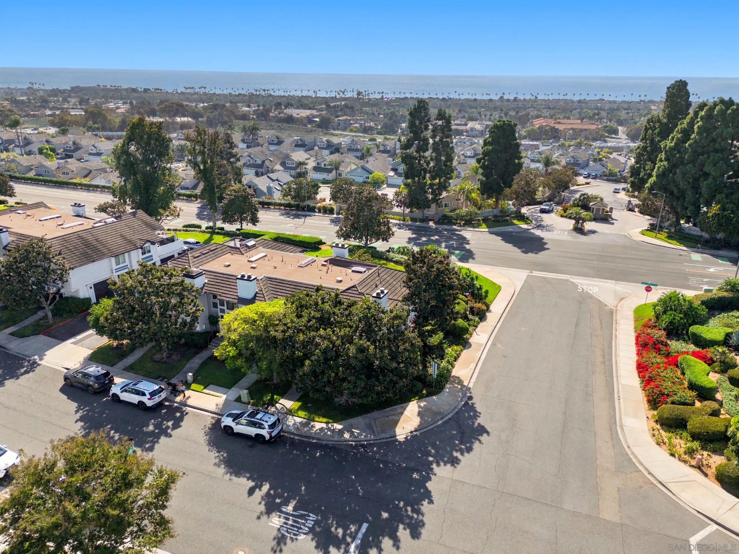 Aerial view of homes near the coast, with the ocean visible beyond the neighborhood.