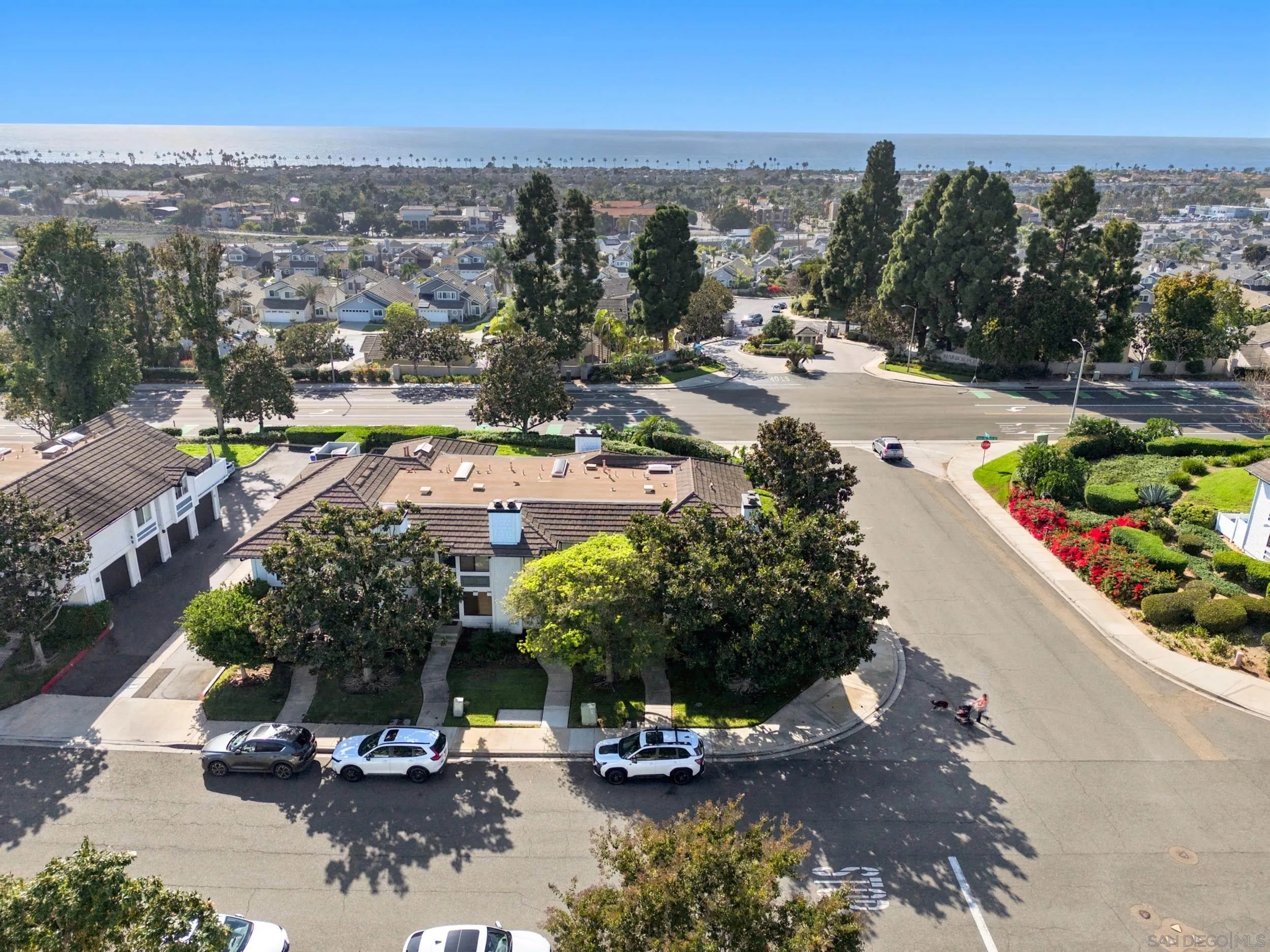 Aerial view of a corner-lot home, with the neighborhood and ocean in the distance.