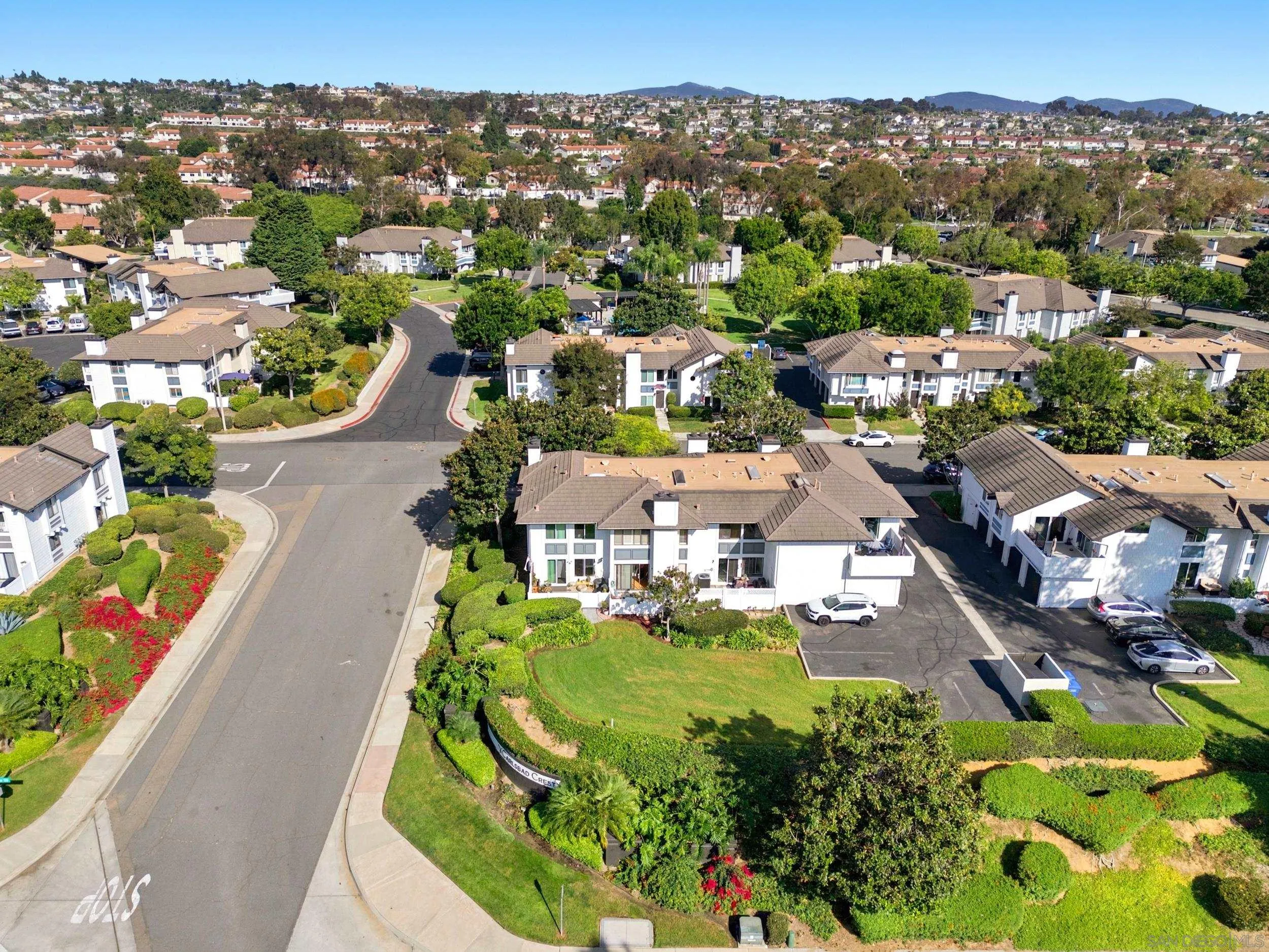 Aerial view of Carlsbad Crest condominiums, landscaped grounds, and surrounding hills.