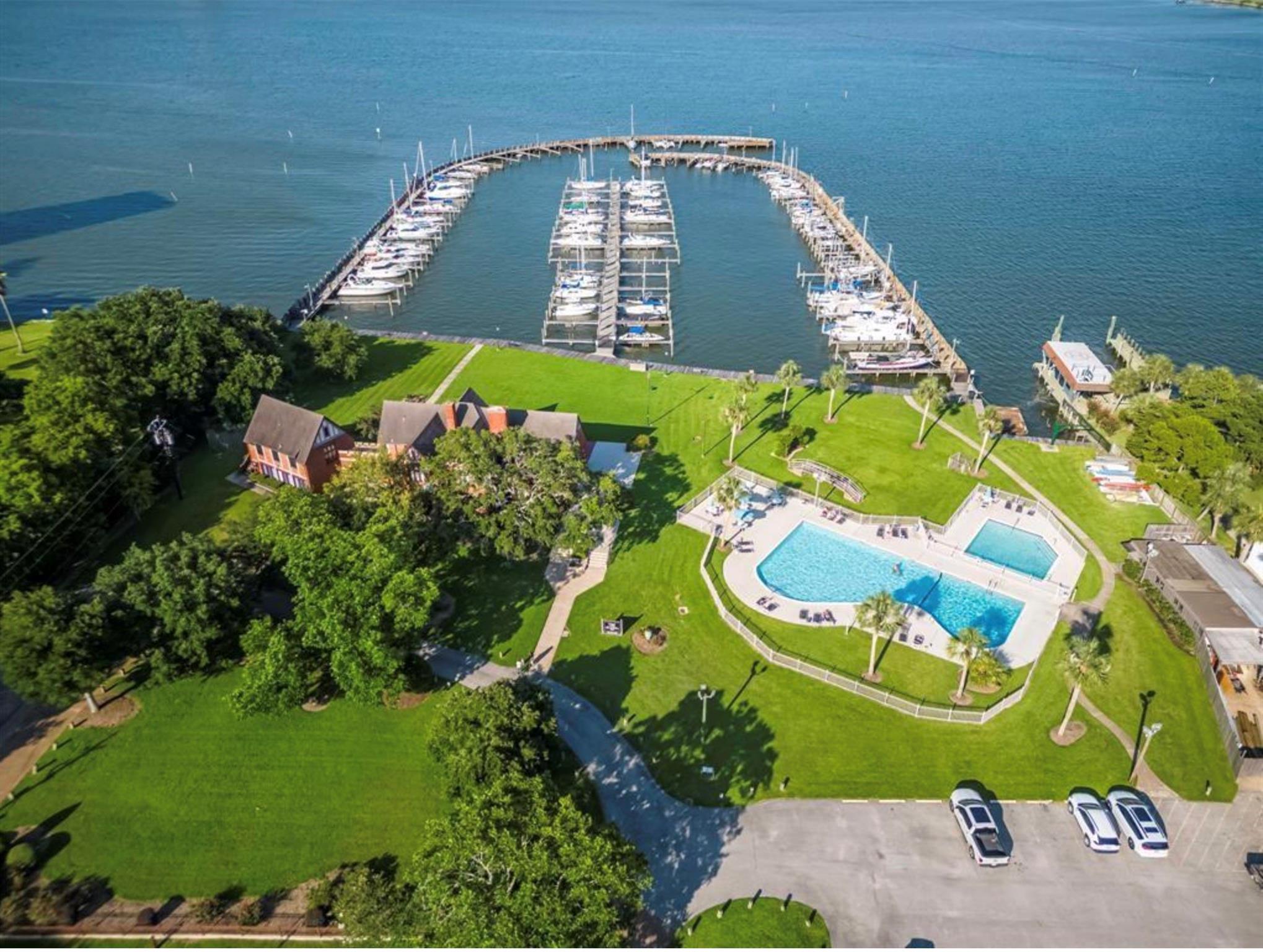 Waterfront community marina and swimming pools surrounded by lawns and palm trees.