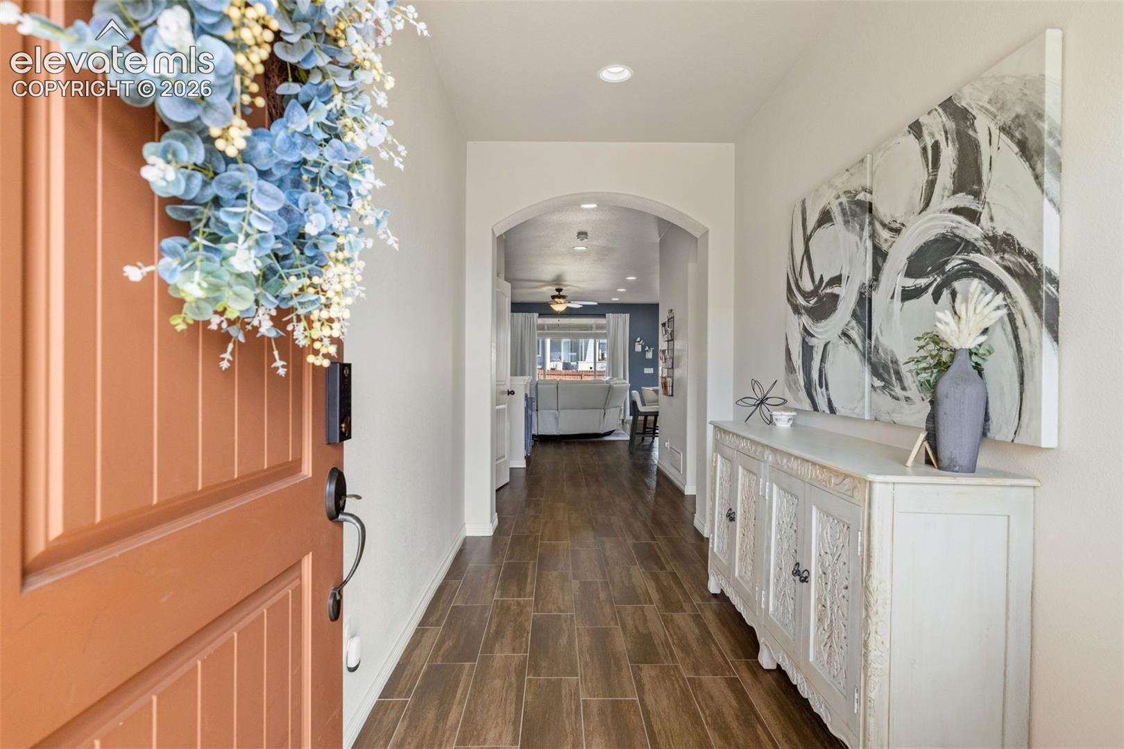 Entry hallway with an open terracotta door, tiled floor, and white console beneath abstract artwork.