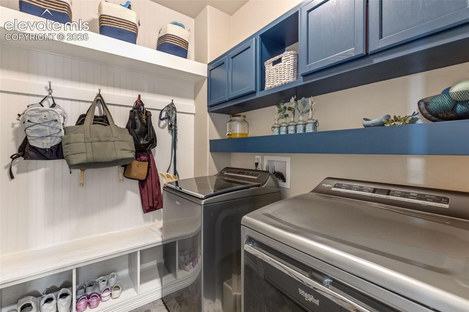 Laundry room with gray appliances, blue cabinets, and built-in coat and shoe storage.