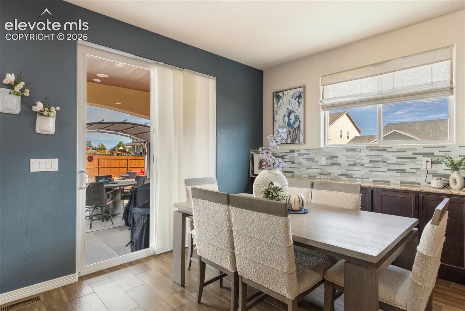 Dining area with a large table and chairs beside sliding doors opening to a covered patio.