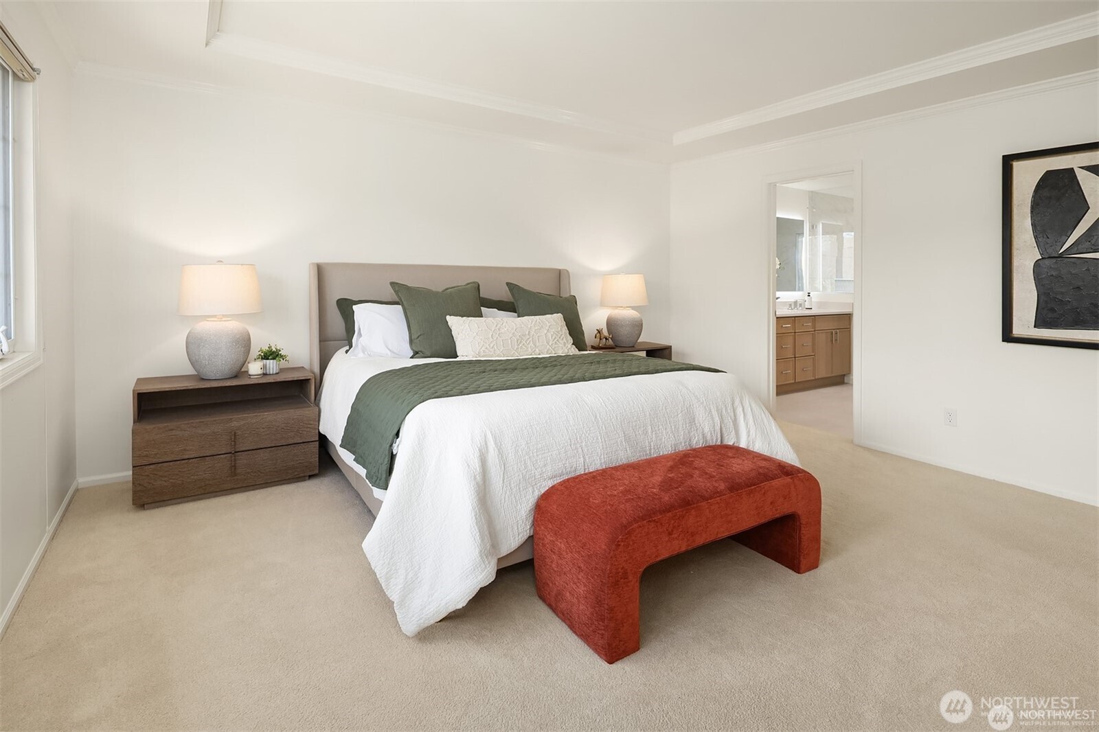 Staged bedroom with a white bed, green accents, and a rust-colored bench.