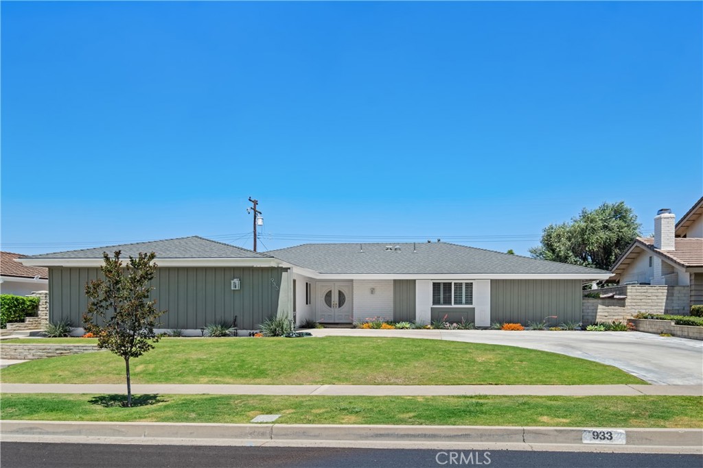 Single-story gray-and-white home with a circular front door and broad lawn.
