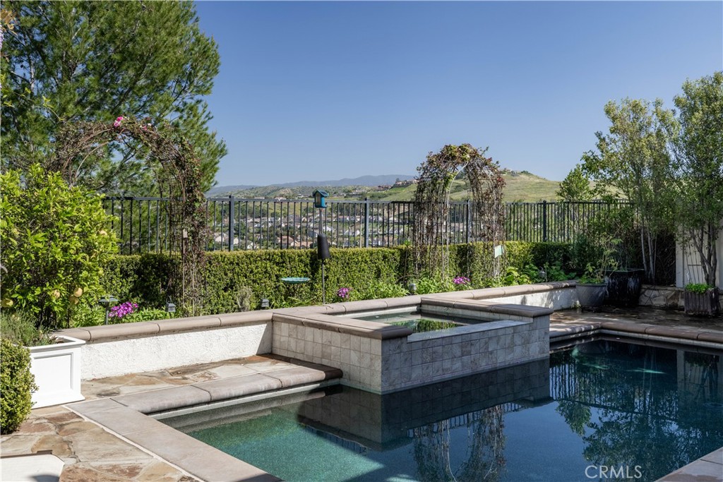 Backyard pool and raised stone spa overlook a neighborhood and rolling hills.