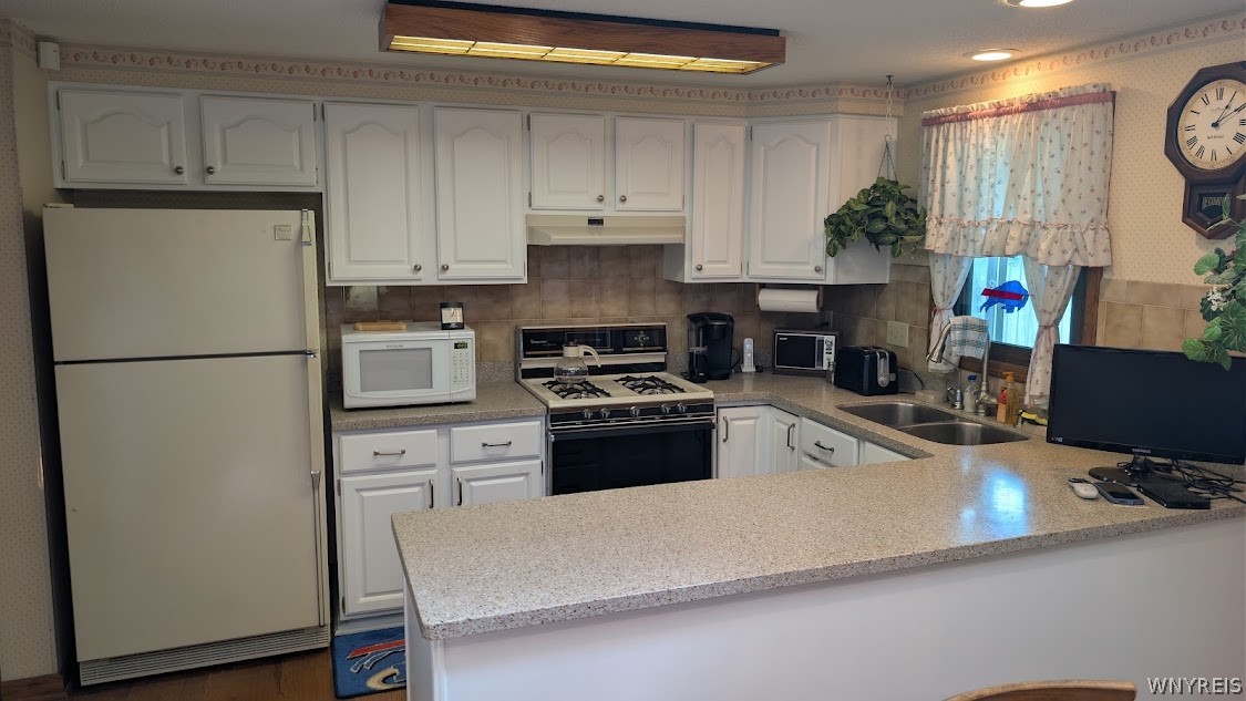 Kitchen with white cabinets, a gas range, and a large speckled countertop peninsula.