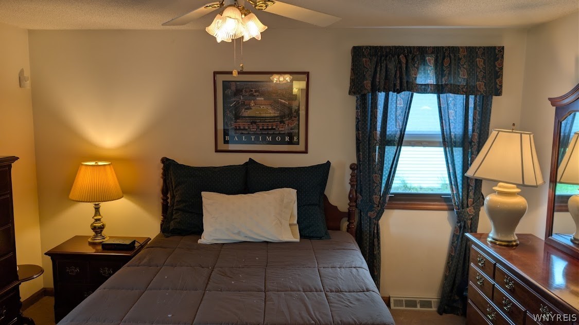 Furnished bedroom with a dark wooden bed, patterned curtains, and matching wooden furniture.