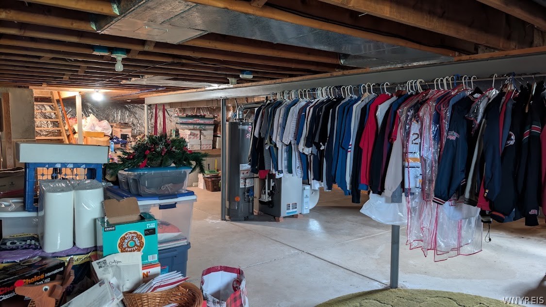 Basement storage area with a long clothing rack, water heater, and exposed ceiling joists.