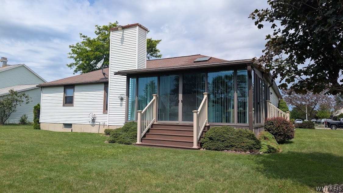 White-sided house with a glass-enclosed sunroom, broad steps, and a lawn.