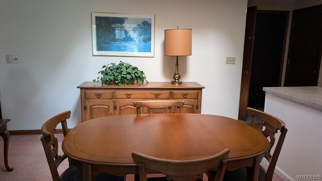 Dining room with an oval wooden table, matching chairs, and a sideboard beneath framed artwork.