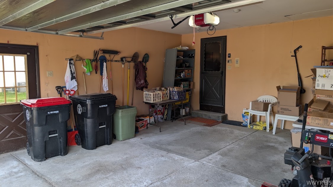 Garage with storage bins, wall-mounted tools, shelving, and a side entry door.