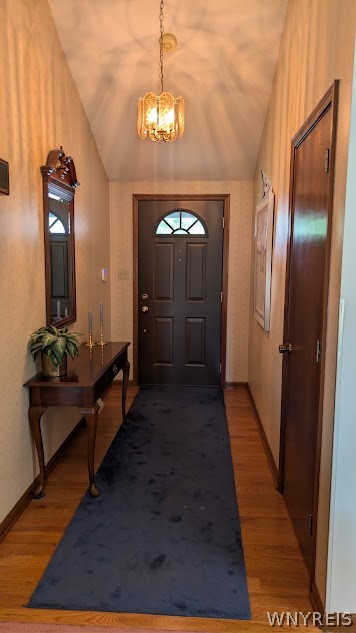 Foyer with a dark front door, arched window, chandelier, and blue runner.