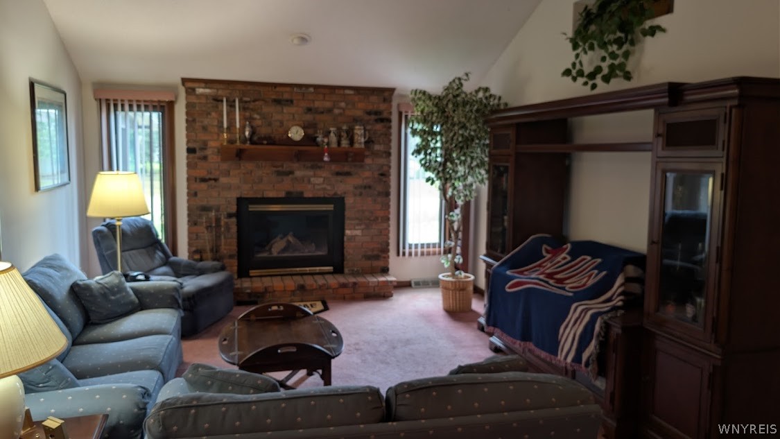 Living room with a brick fireplace, blue seating, and dark built-in cabinetry.