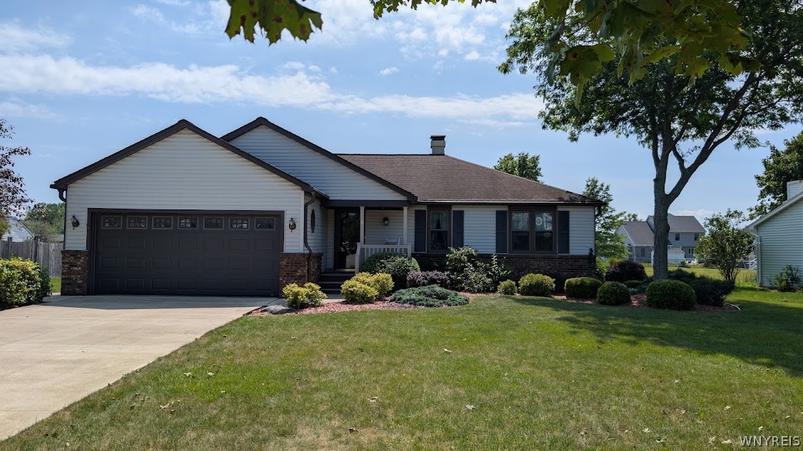 Single-story house with an attached two-car garage, landscaped front garden, and broad lawn.