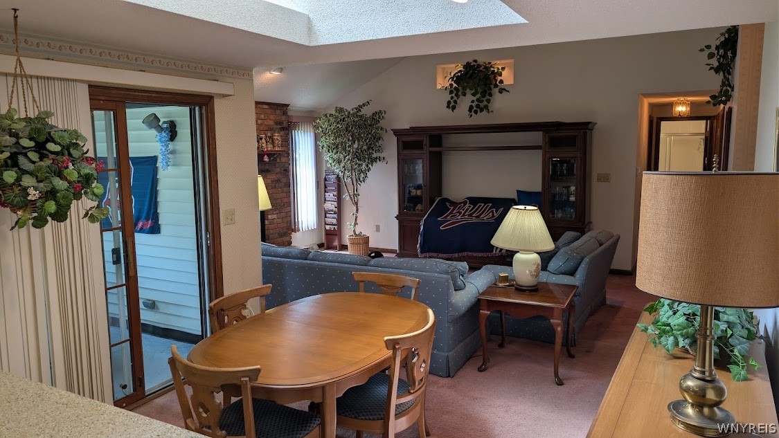 Dining and living area with a wooden table, blue sofas, and a large skylight.