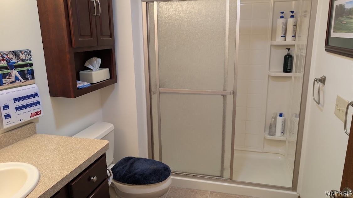 Bathroom with a frosted sliding shower door, dark wood cabinetry, and a beige vanity countertop.