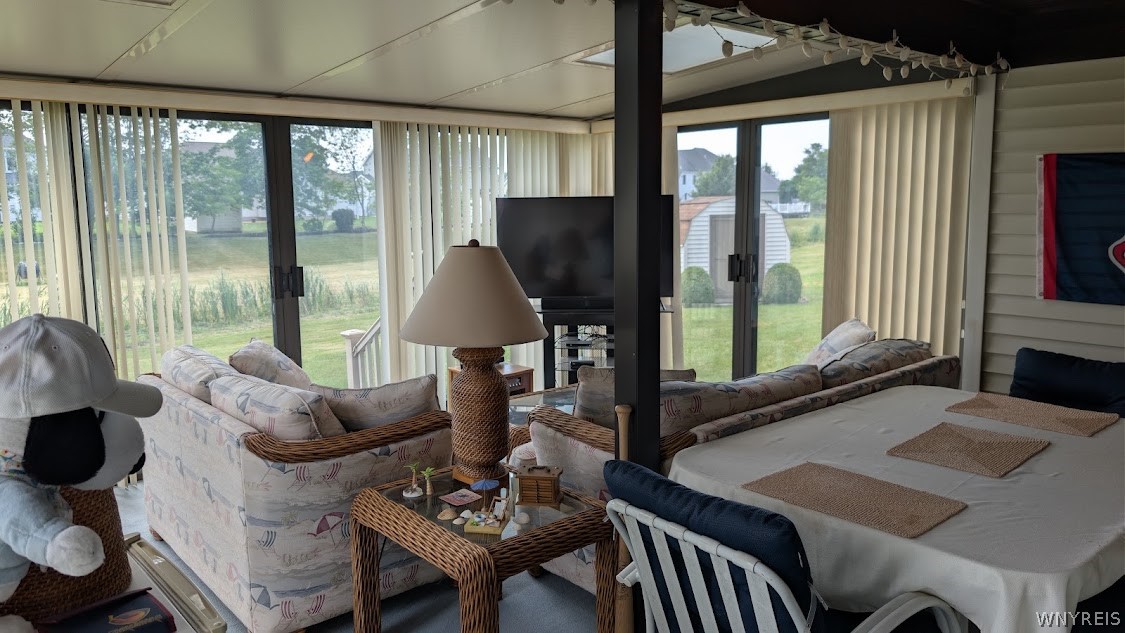 Enclosed sunroom with wicker seating, dining table, and large windows overlooking the backyard.