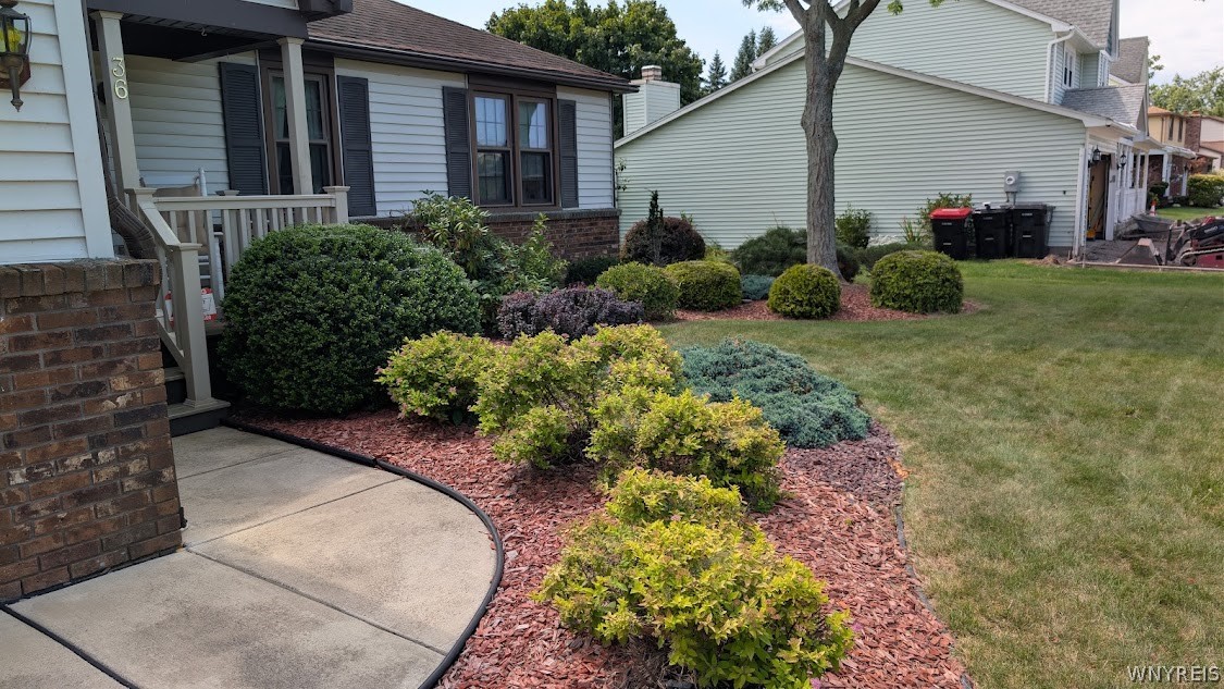 Home exterior with a covered porch, brick accents, and landscaped beds beside a curved walkway.