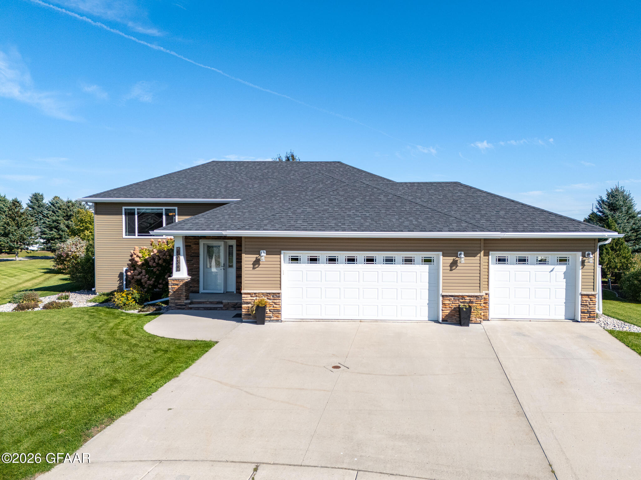 Home at 3934 Cedar Circle with two white garage doors, stone accents, and a wide driveway.