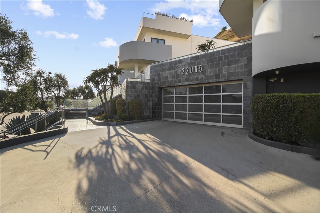 Contemporary home with a dark stone garage facade and broad concrete driveway.