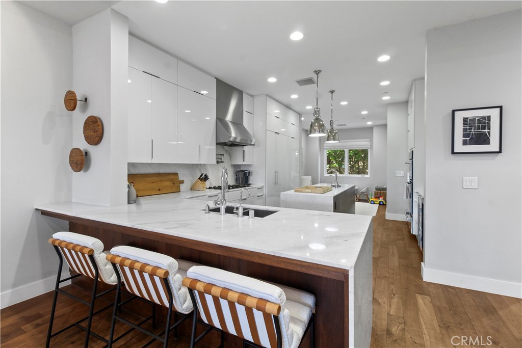 Modern kitchen with a large white island, dark wood breakfast bar, and upholstered stools.
