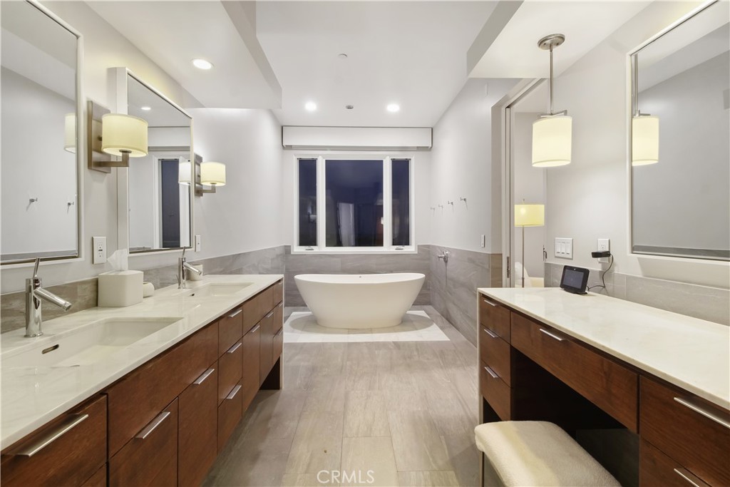 Modern bathroom with a freestanding soaking tub and dual wood vanities.