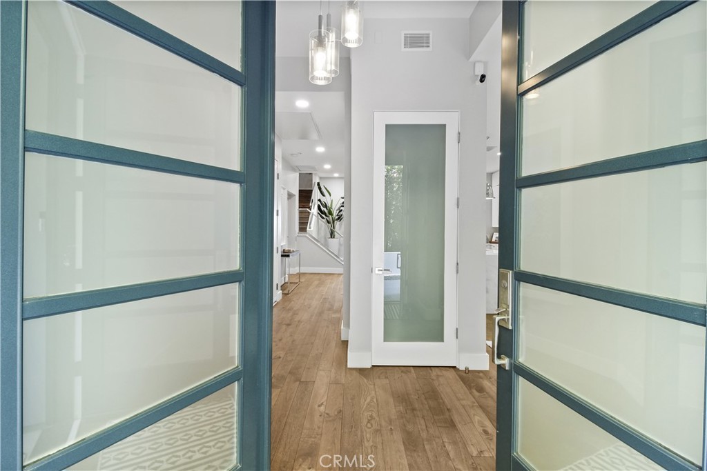 Entryway with blue-framed glass doors, wood floors, and a white frosted-glass door.