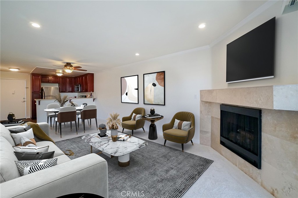 Open-plan living room with a stone fireplace, light sectional sofa, and adjoining dining area and kitchen.