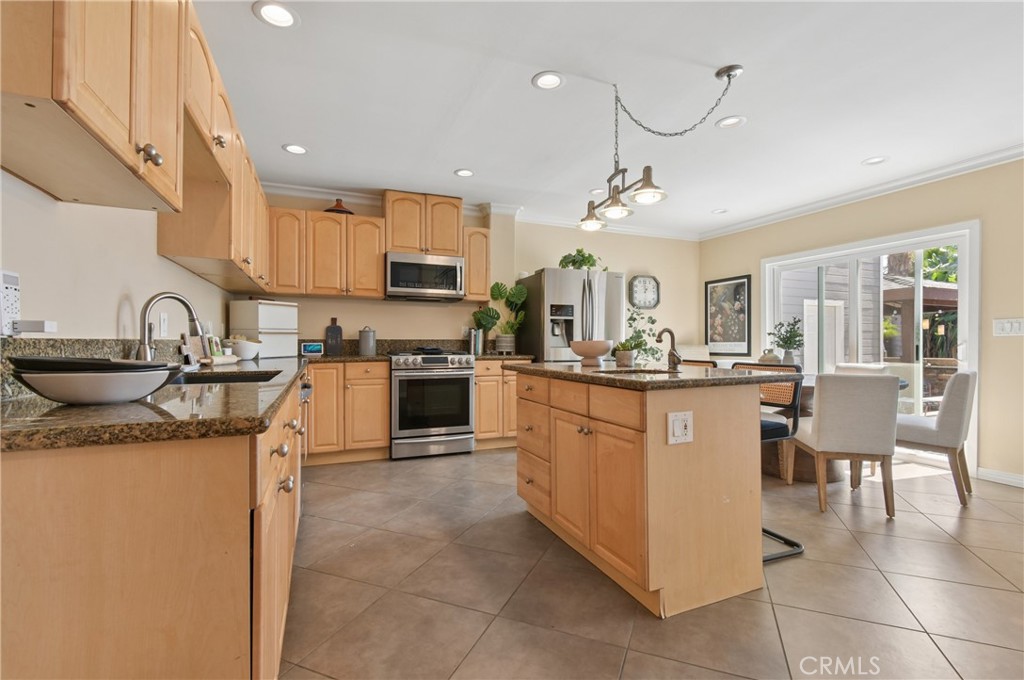 Kitchen with a central island, granite counters, and sliding glass doors beside the dining area.