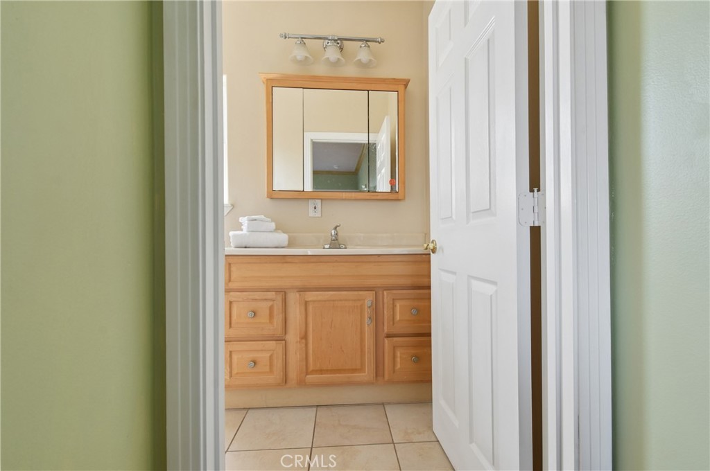 Bathroom vanity with light wood cabinetry, mirrored cabinet, and folded white towels.