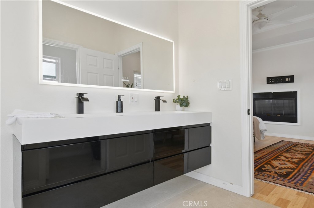 Bathroom with a floating black double vanity, white countertop, and wide mirror.