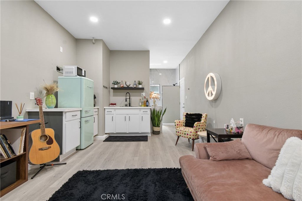 Open-plan living room and kitchen with a mint-green refrigerator and pink sofa.