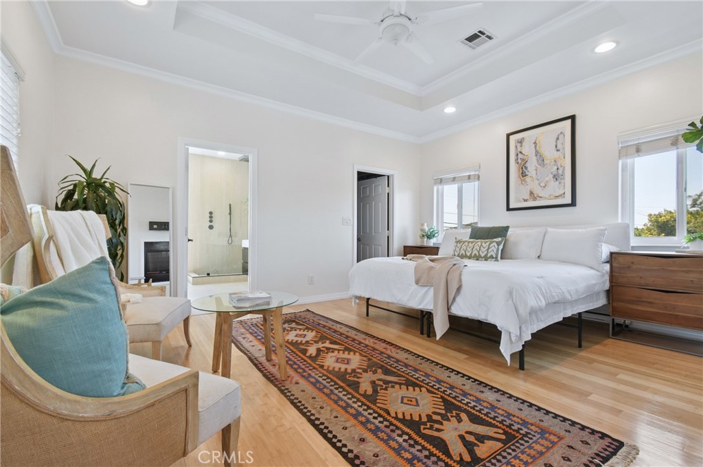 Staged bedroom with a large white bed, patterned rug, and open doorway to an adjoining bathroom.