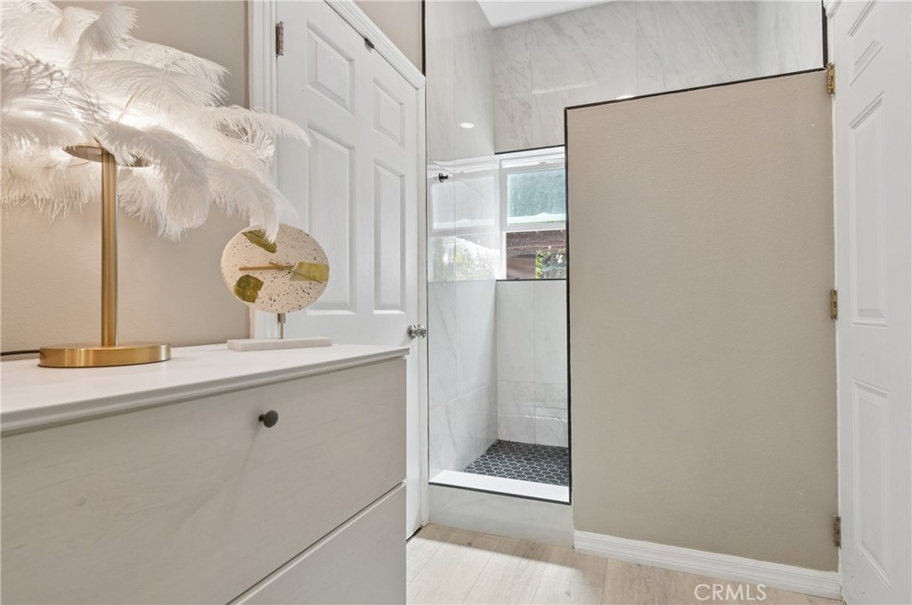 Bathroom with a white vanity and glass shower featuring marble-look tile and a dark hexagonal floor.