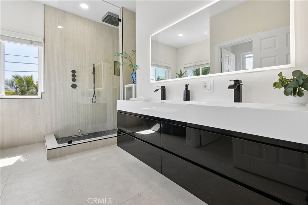 Modern bathroom with a glass walk-in shower and glossy black double vanity.