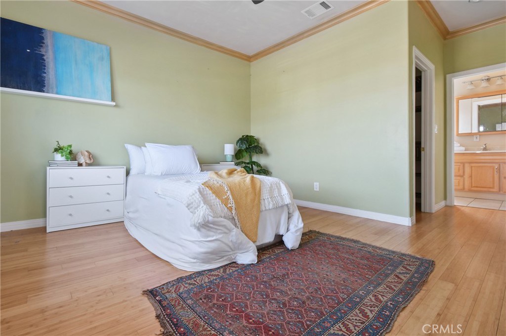 Furnished bedroom with a white bed, patterned rug, and bathroom visible through the doorway.