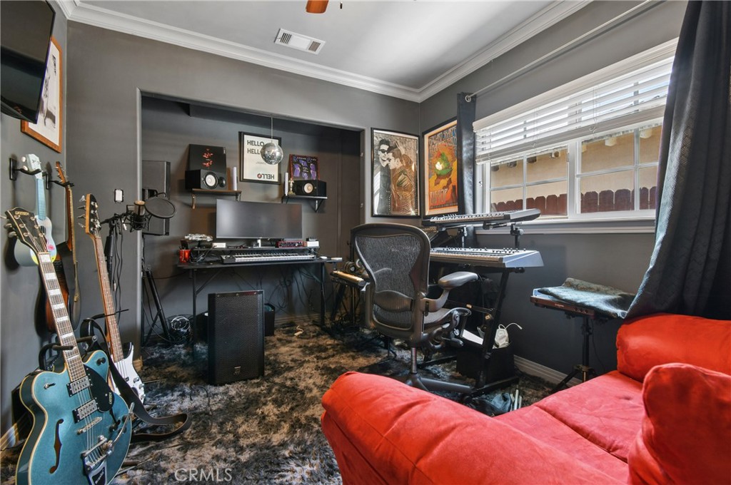 Music studio with guitars, keyboards, recording equipment, and a red sofa.