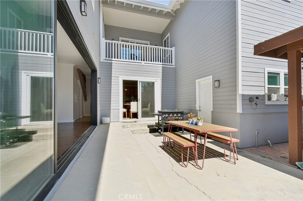 Courtyard patio with a picnic table and grill beneath a second-story balcony.