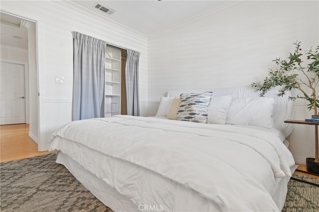 Bedroom with a large white bed, gray curtains, built-in shelving, and a patterned rug.