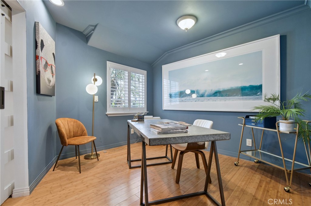 Dining room with blue walls, a stone-top table, hardwood floors, and large wave artwork.