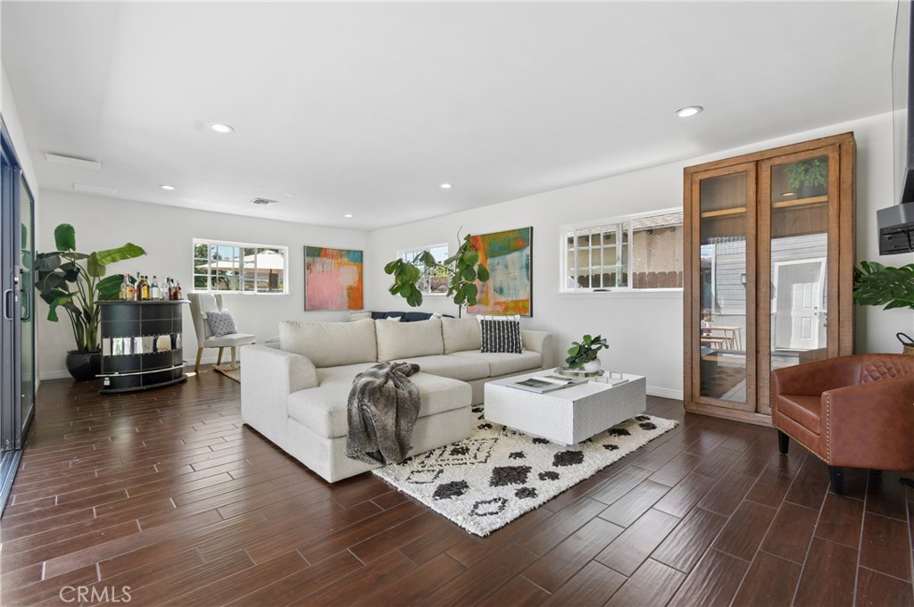 Living room with a white sectional, patterned rug, abstract art, and dark tile flooring.