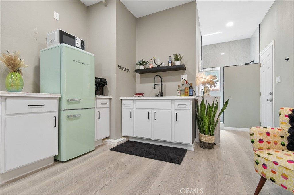 Kitchenette with white cabinets, mint-green refrigerator, and black faucet