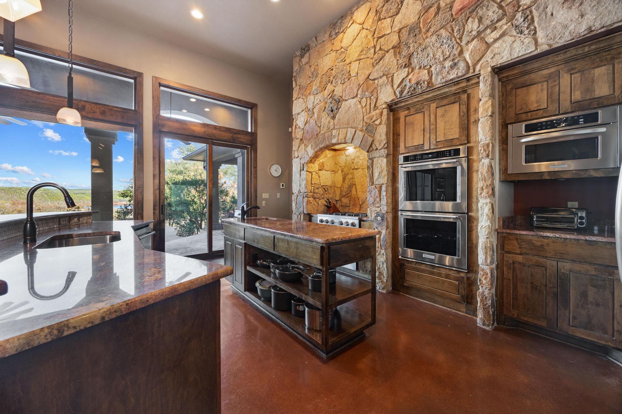 Kitchen with a stone cooking alcove, dark wood cabinetry, and windows overlooking water.