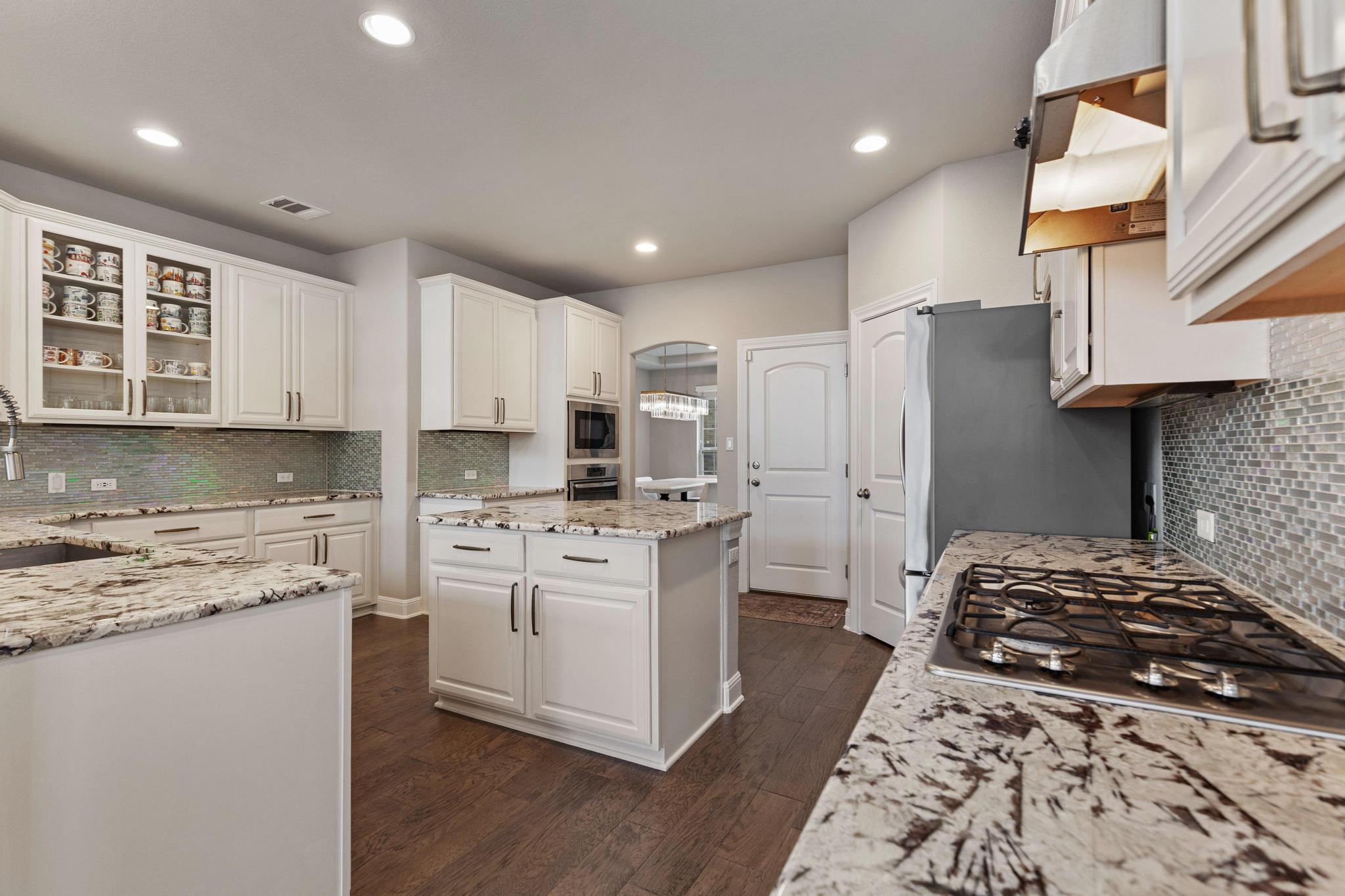 Kitchen with white cabinets, granite counters, a central island, and a gas cooktop.