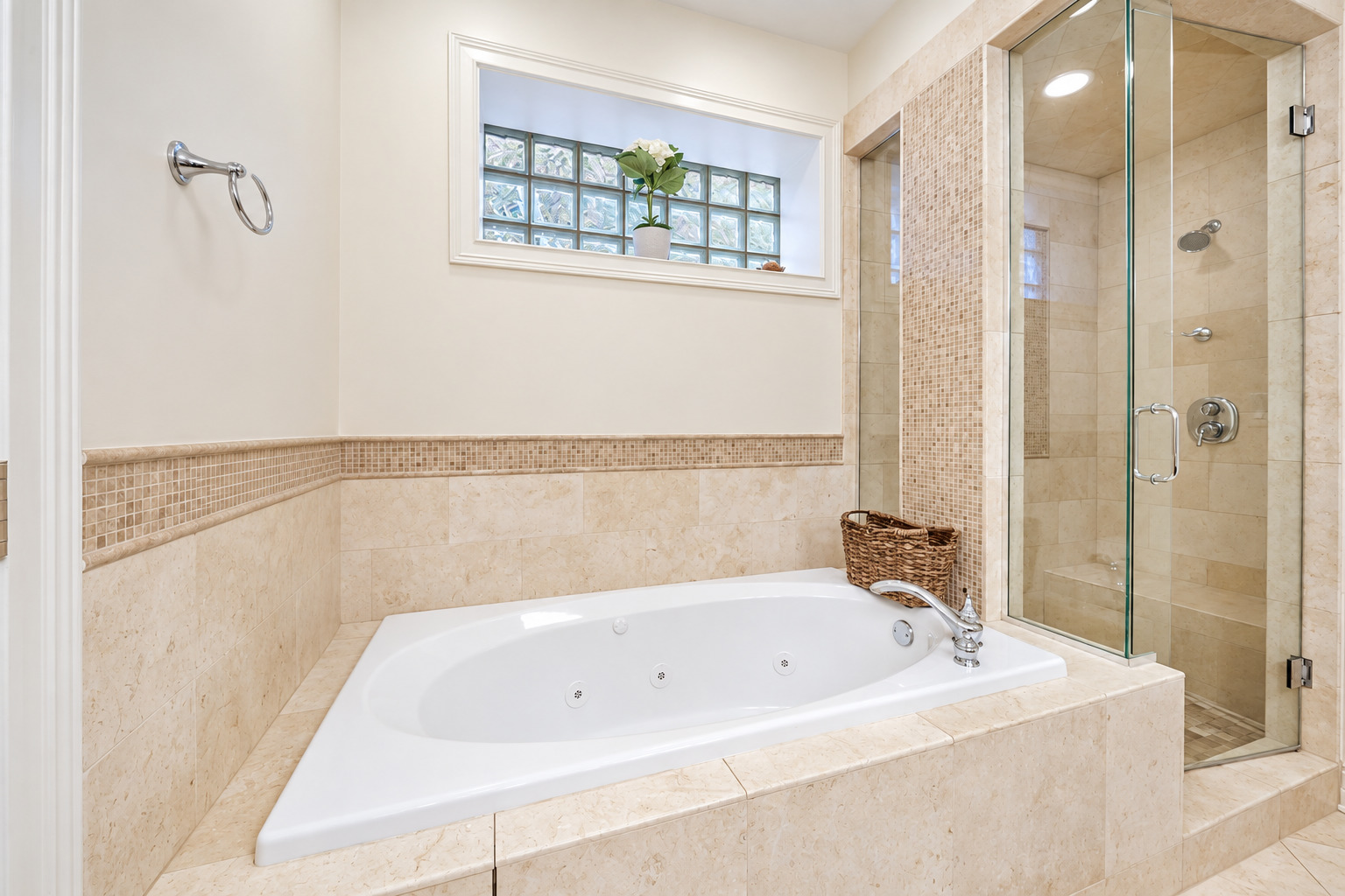 Bathroom with a jetted soaking tub, glass-enclosed shower, and glass-block window.