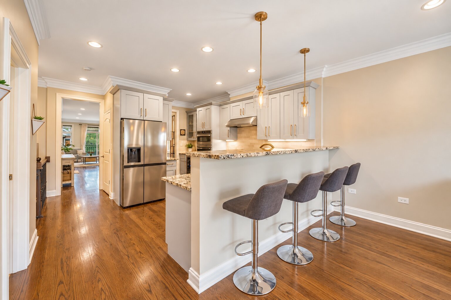 Kitchen with white cabinets, stainless steel appliances, and a stone breakfast bar with gray stools.